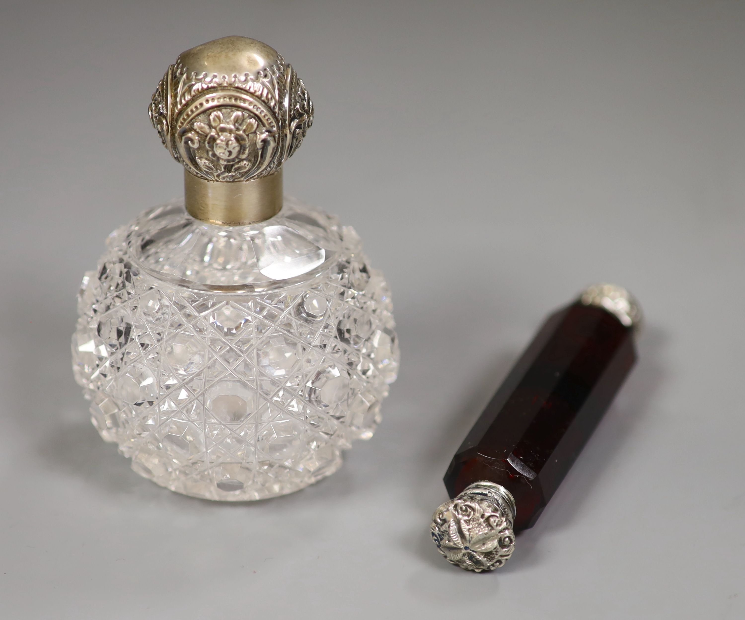 An Edwardian silver mounted glass toilet jar, 10.3cm and a white metal mounted ruby glass double scent bottle.